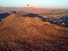 Shadows grow long as the sun dips low on the horizon. Afternoon hot air balloon flights in Phoenix offer a great vantage point to watch the sun set.